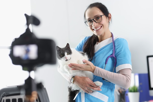 Sonriente médico veterinario demuestra gato a la cámara