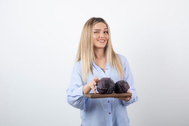 sonriente modelo de mujer bonita de pie y sosteniendo el repollo.