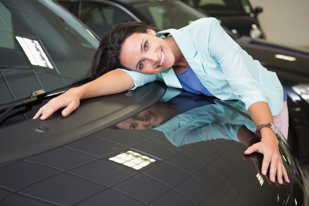 Foto sonriente mujer abrazando un auto negro