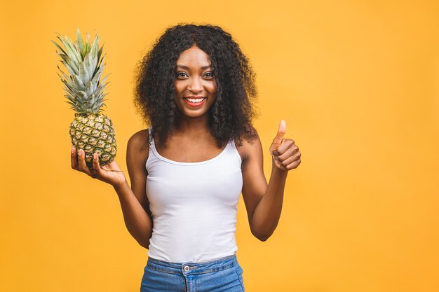 Sonriente mujer africana americana sosteniendo una piña