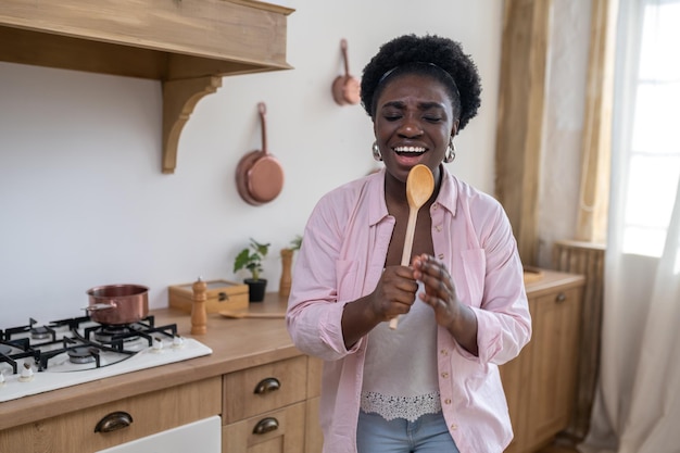 Sonriente mujer africana cantando y mirando disfrutada