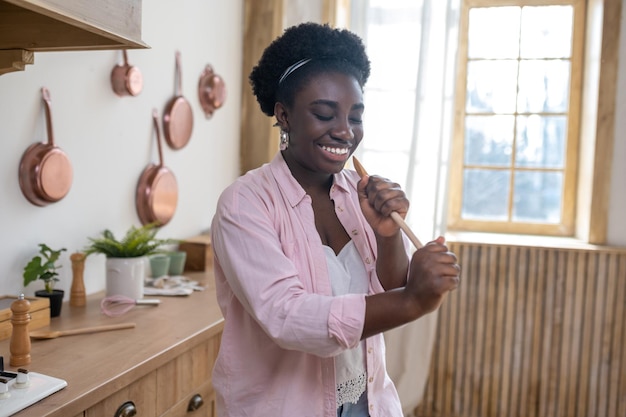 Sonriente mujer africana cantando y mirando disfrutada