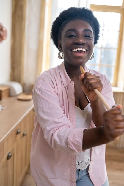 Sonriente mujer africana cantando y mirando disfrutada