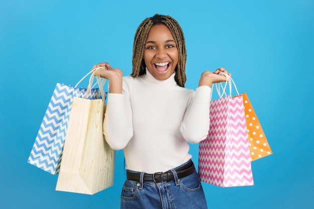 Sonriente mujer africana felizmente llevando bolsas de compras