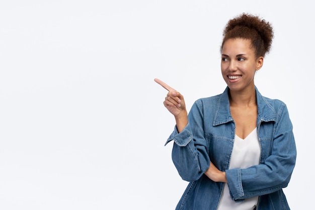 Sonriente mujer afroamericana con ropa informal señalando con el dedo en el espacio de copia