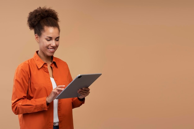 Sonriente mujer afroamericana usando tableta digital aislada sobre fondo beige, espacio de copia