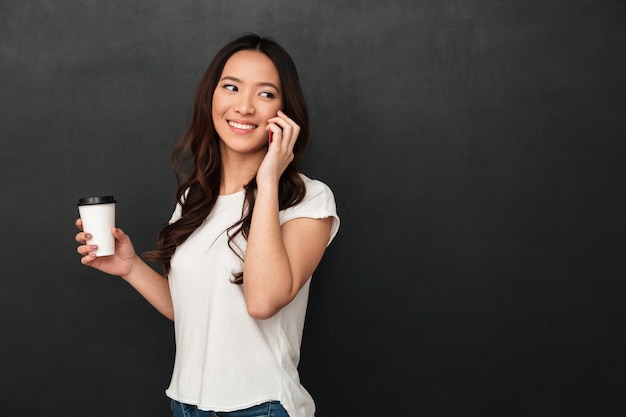 Sonriente mujer asiática en camiseta con taza de café