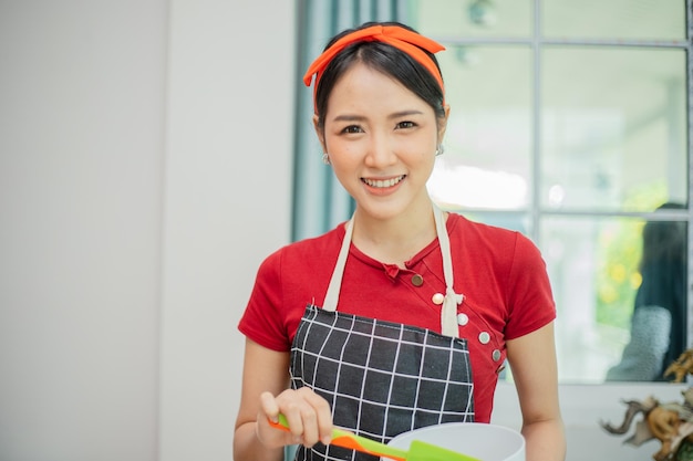 Sonriente mujer asiática cocinando y mirando a cámara