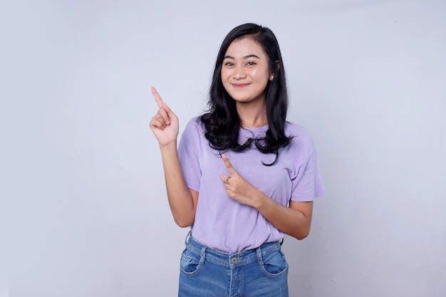 Sonriente mujer asiática feliz con su dedo apuntando aislado sobre fondo de banner blanco claro con espacio de copia