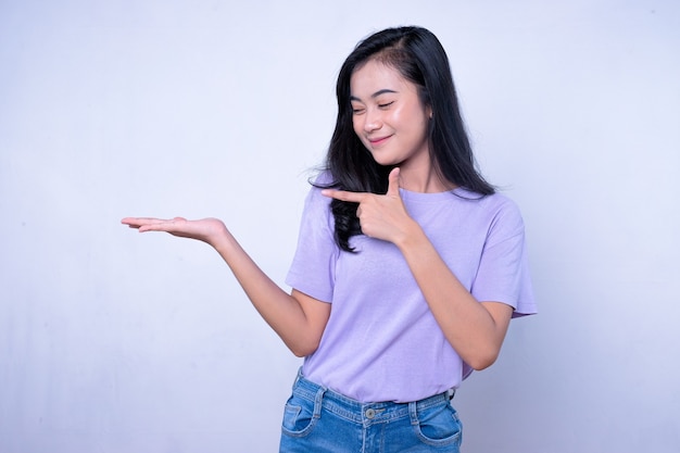 Sonriente mujer asiática feliz con su dedo izquierdo apuntando y mostrando aislado sobre fondo de banner blanco claro con espacio de copia