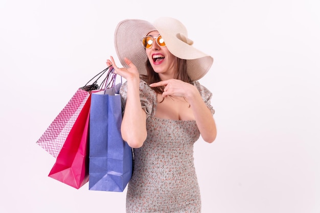 Sonriente mujer atractiva sosteniendo bolsas de compras sobre fondo blanco con copyspace