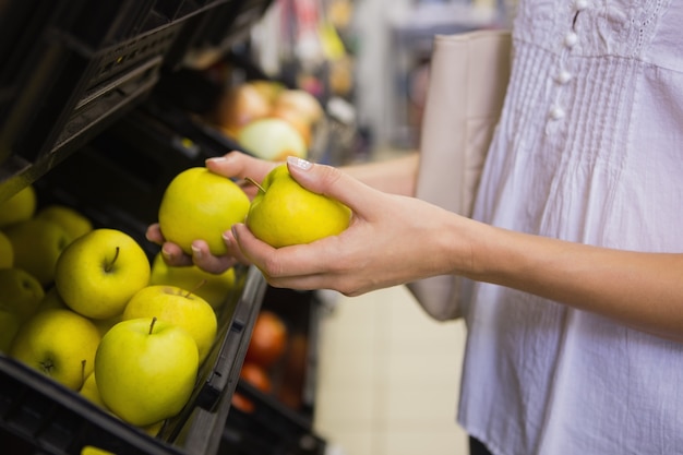 Sonriente mujer bonita rubia comprando manzanas