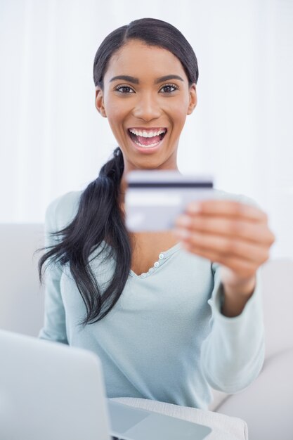 Sonriente mujer bonita usando su computadora portátil para comprar en línea