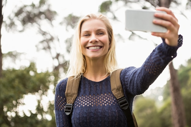 Sonriente mujer caminante tomando un selfie