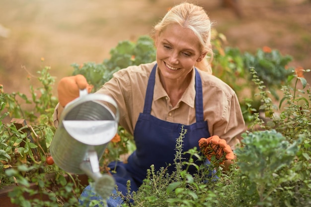 Sonriente mujer caucásica de mediana edad regar las plantas