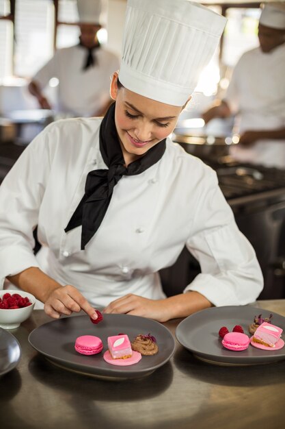 Sonriente mujer chef terminando platos de postre