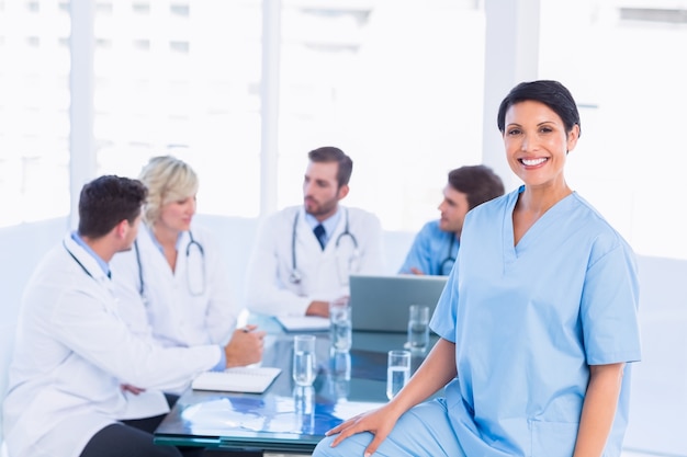 Sonriente mujer cirujano con colegas en reunión