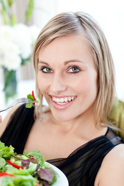 Sonriente mujer comiendo una ensalada