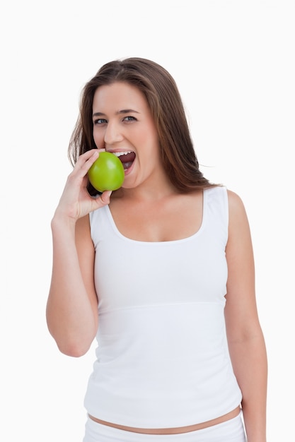 Sonriente mujer comiendo una manzana verde