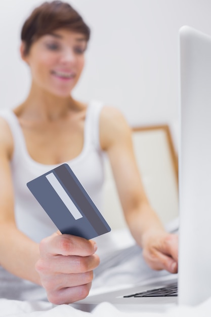 Sonriente mujer de compras en línea en la cama