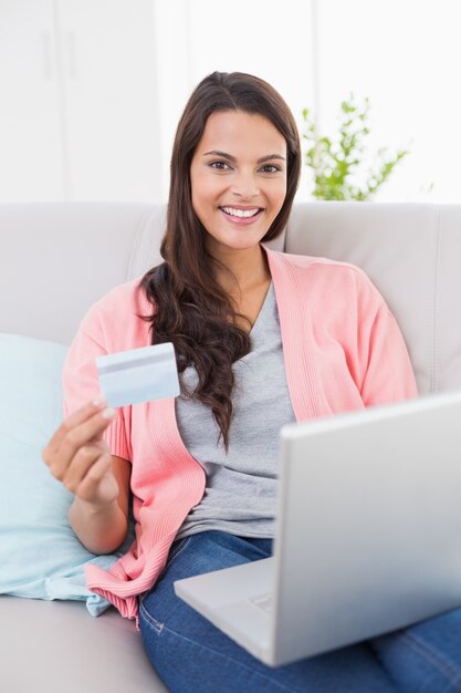 Sonriente mujer de compras en línea a través de la computadora portátil con tarjeta de crédito