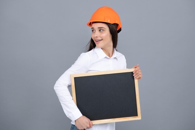 Sonriente mujer constructora de negocios con retrato de tablero en gris