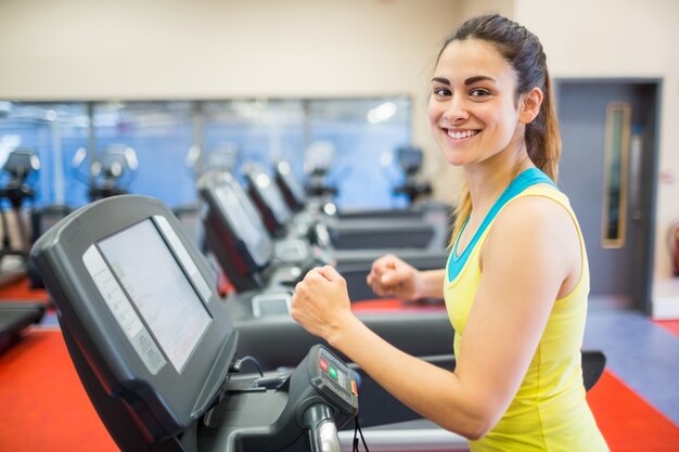 Sonriente mujer corriendo en una cinta de correr