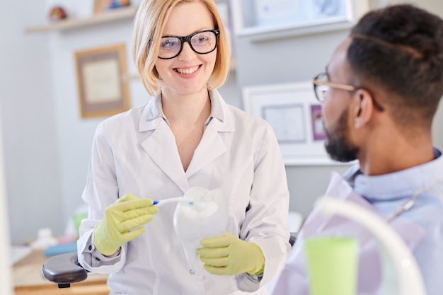 Sonriente mujer dentista con cepillo de dientes