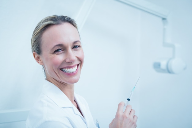 Sonriente mujer dentista con inyección