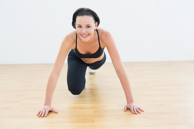 Sonriente mujer deportiva haciendo flexiones en el gimnasio