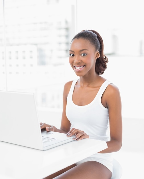 Sonriente mujer deportiva usando su computadora portátil