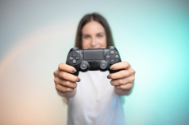 Sonriente mujer divertida sosteniendo el controlador de la consola en colores de fondo. Persona adulta joven disfrutando