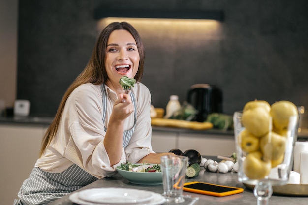 Sonriente mujer feliz comiendo con apetito