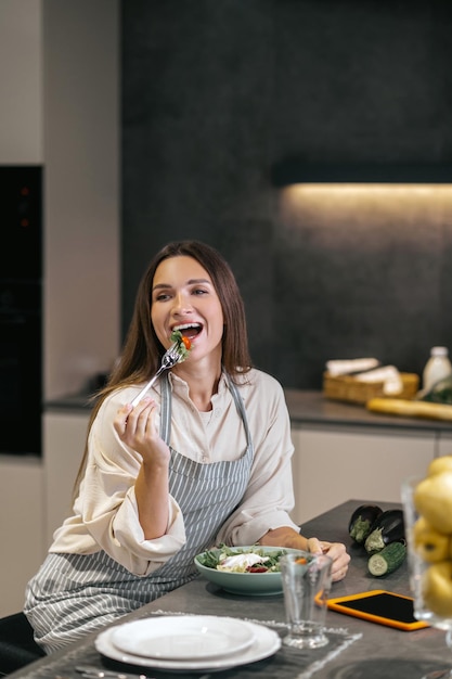 Sonriente mujer feliz comiendo con apetito