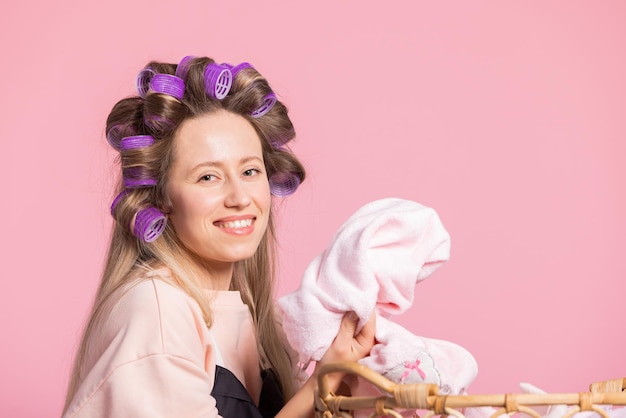 Sonriente mujer feliz de fondo rosa olfatea ropa limpia lavada que huele a frescura en polvo