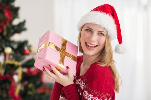 Sonriente mujer festiva mostrando un regalo rosa