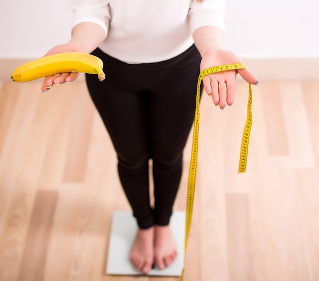 Sonriente mujer en forma con escala y manzana