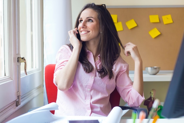 Foto sonriente mujer hablando por teléfono en el trabajo