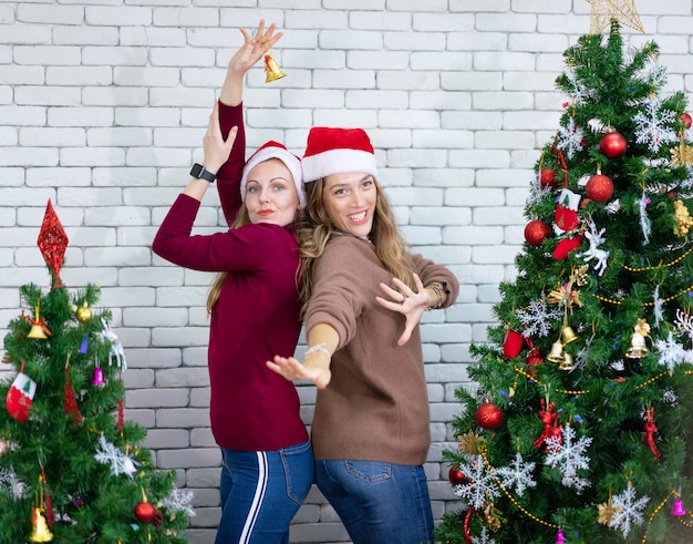 Sonriente mujer hermosa bailando alrededor de un árbol de Navidad decorado, antes de la víspera de Año Nuevo en casa, celebración navideña