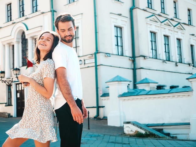 Sonriente mujer hermosa y su guapo novio Mujer en ropa casual de verano Familia alegre feliz Mujer divirtiéndose Pareja posando en el fondo de la calle Abrazándose unos a otros al atardecer