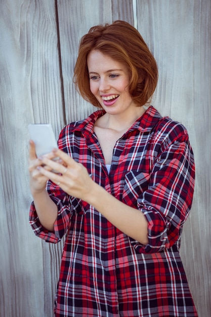 sonriente mujer hipster en su teléfono inteligente