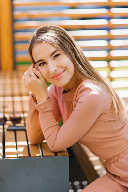 Sonriente mujer joven atractiva sentada en el bar en un café de la calle