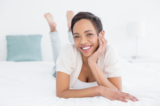 Sonriente mujer joven y bonita relajante en la cama