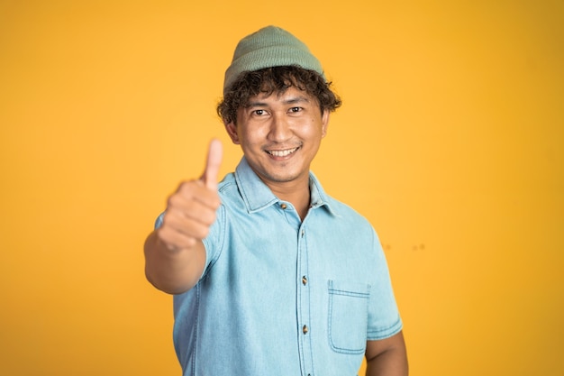 Sonriente mujer joven de pie con los pulgares hacia arriba en aislado