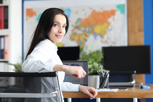 Sonriente a mujer joven sentada en el lugar de trabajo closeup