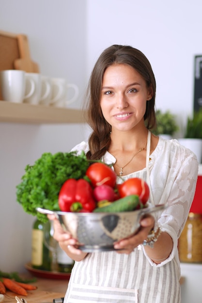 sonriente, mujer joven, tenencia, vegetales, posición, en, cocina