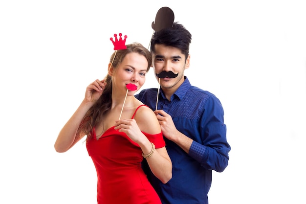 Sonriente mujer joven en vestido y joven guapo en camisa con palos de cartón de bigotes