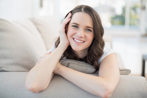 Sonriente mujer linda acostada en un sofá acogedor