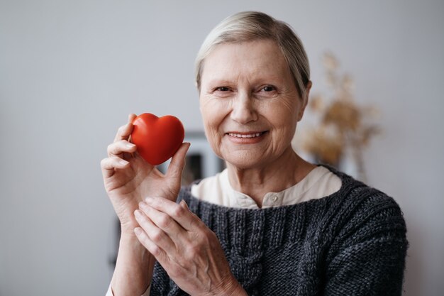 Sonriente mujer madura con un corazón rojo en sus manos