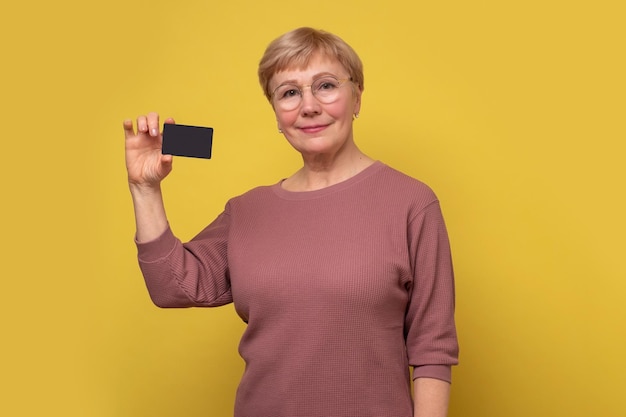 Sonriente mujer madura que muestra la tarjeta vacía en la mano